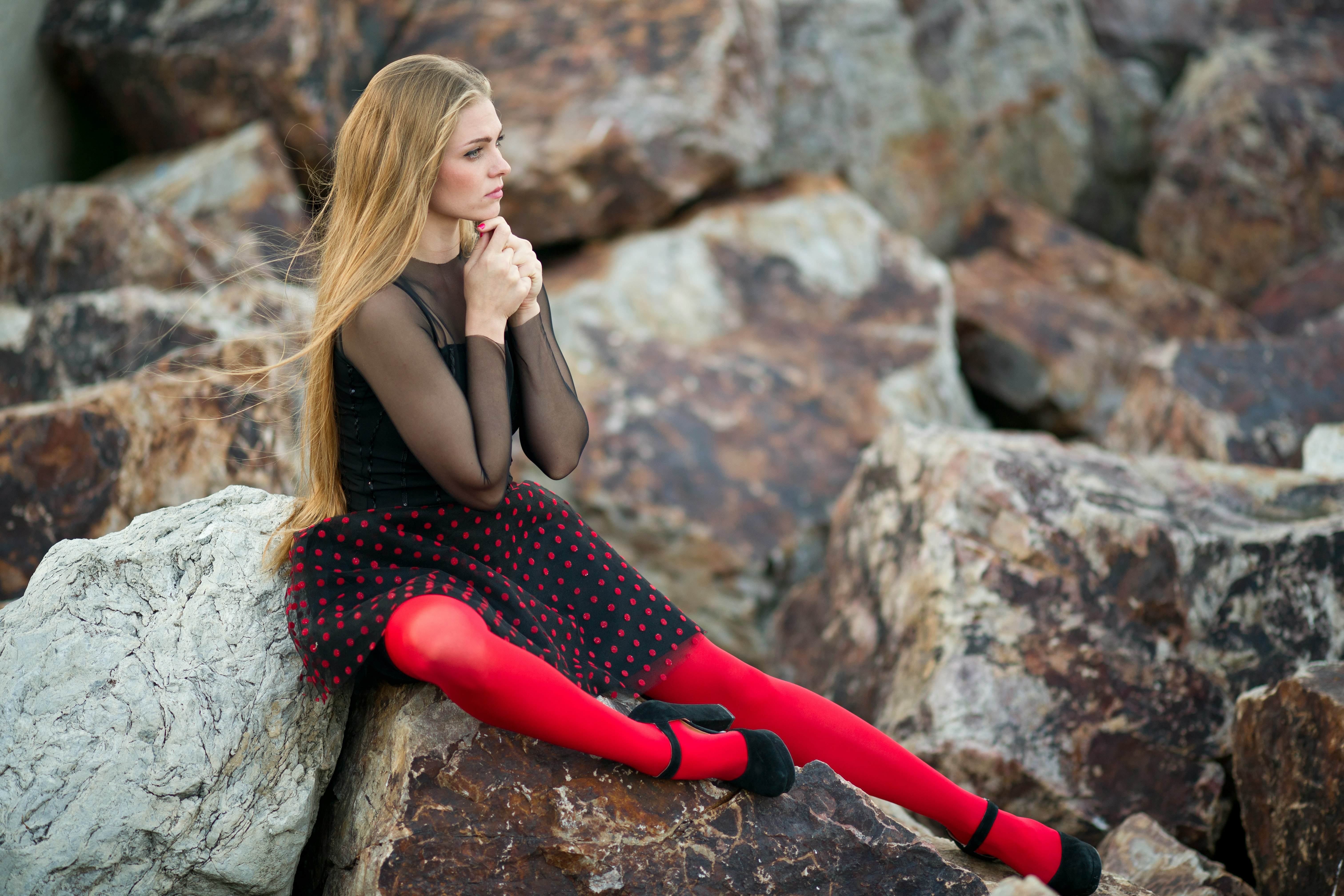 woman in black sleeveless dress sitting on gray rock